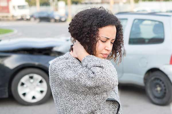 una señora sostiene su cuello con dolor después de un accidente automovilístico