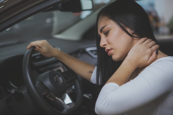 female driver holds her neck in pain after car accident